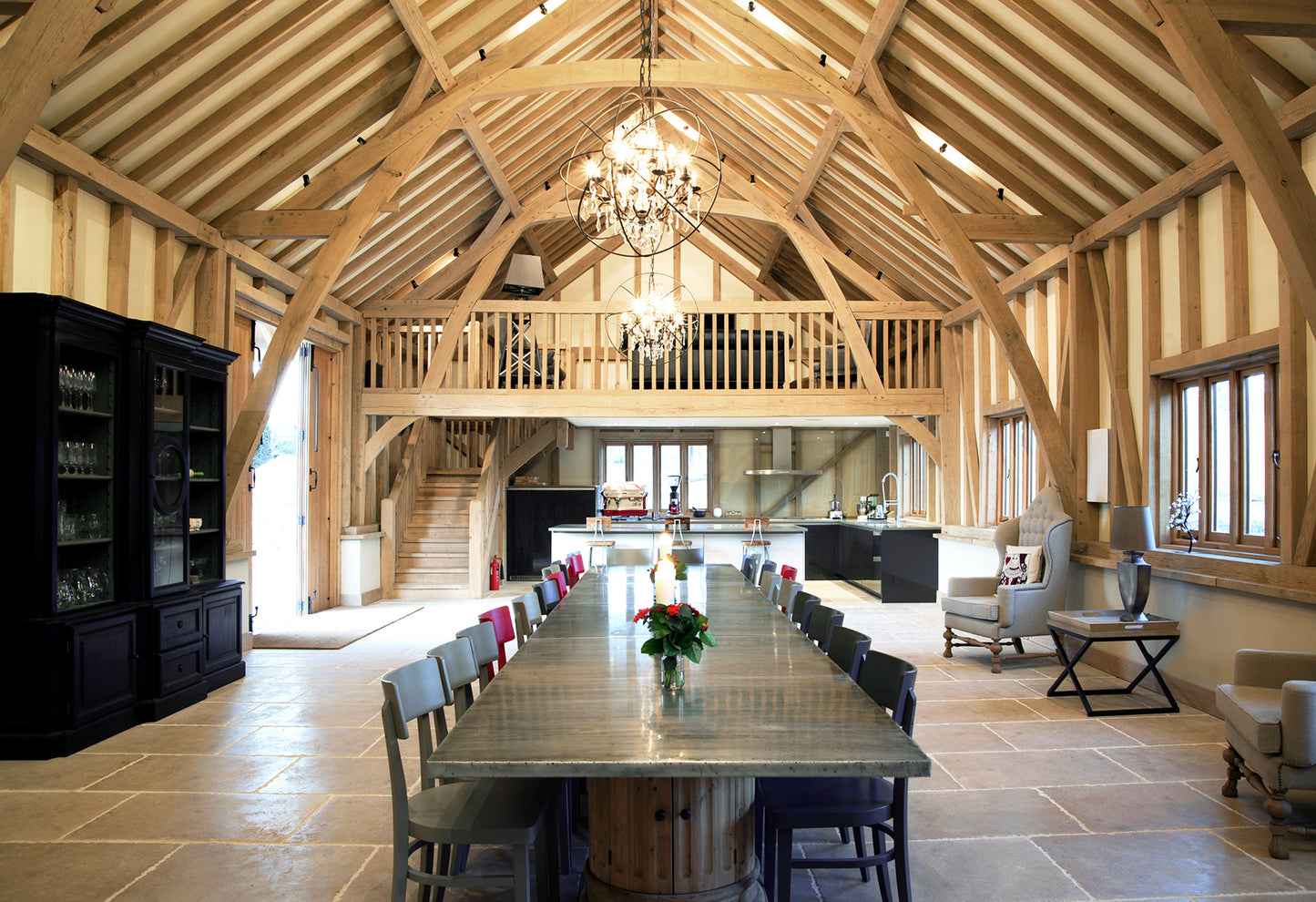 Enjoy a spacious open-plan dining and kitchen area in a barn conversion with exposed beams, modern chairs, and chandeliers—perfect for hosting the Event Pancake Day Special - Dosa Masterclass from fermented rice and lentil batter.