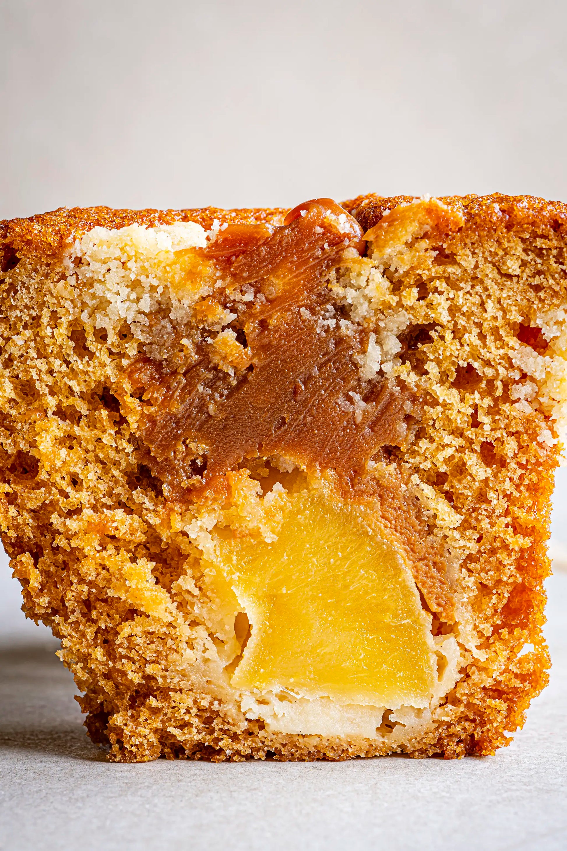 Close-up of Honesty’s Apple & Caramel Muffin, sliced to display its golden-brown crumb with rich caramel swirls and a piece of apple inside, set against a softly lit, plain background.