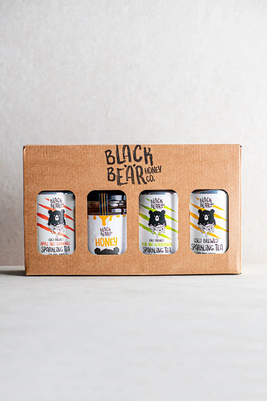 The Honesty Black Bear Honey Co. Gift Pack includes three cans of Cold Brewed Sparkling Tea and a jar of pure honey, each with a bear logo and colorful stripes, presented against a plain background.