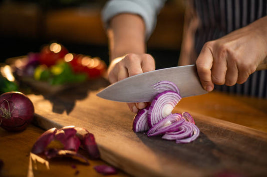 With the Event All in One Pot, prep for midweek meals is easy—slice red onions and veggies on a wooden board, ready to add fresh ingredients straight to your dish. The softly blurred background highlights convenient countertop prep.
